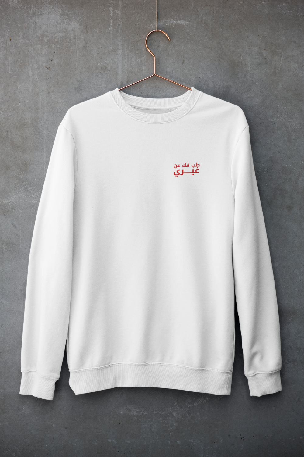 A crewneck sweatshirt hanging against a concrete wall