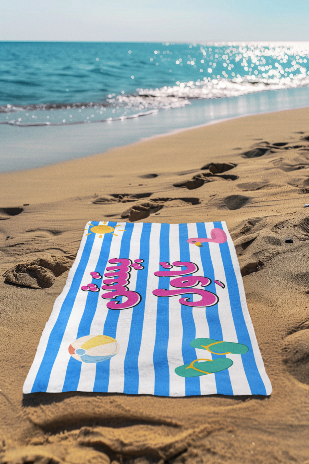 Striped beach towel with colorful text and graphics on a sandy beach with ocean in the background