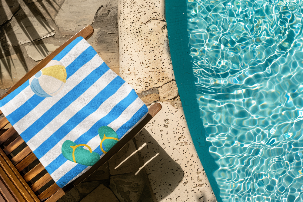 Blue and white striped towel with beach-themed design on a wooden chair by a pool.