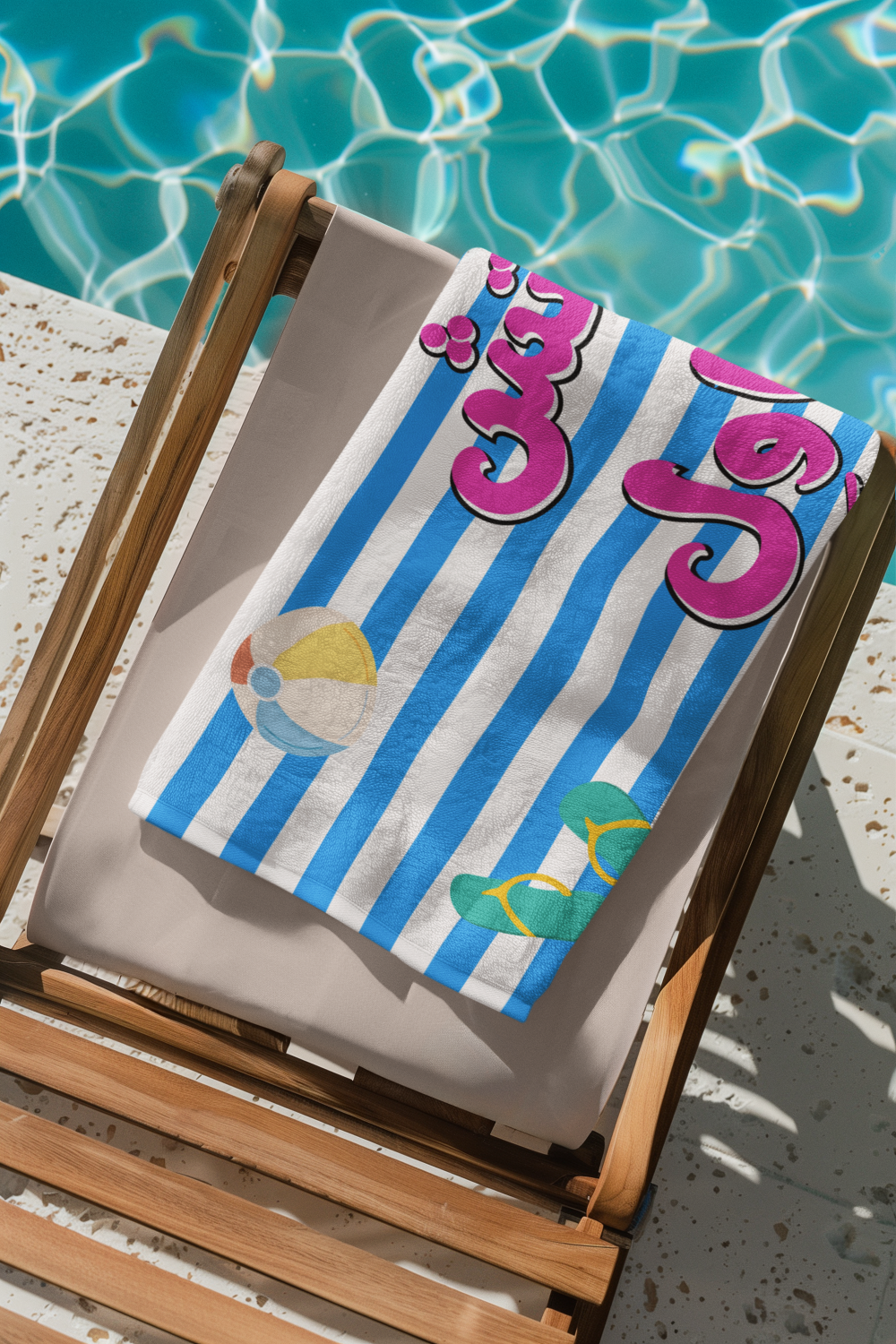 Beach towel with blue stripes and colorful graphics on a wooden deck chair by a pool.