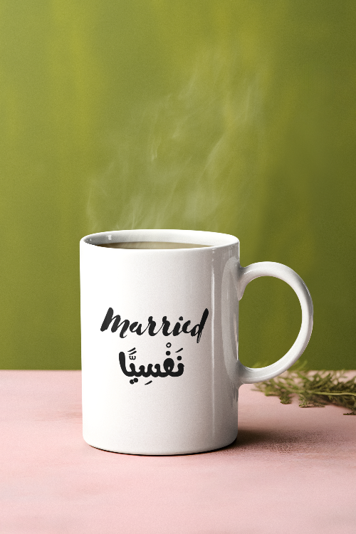 White mug with 'married' text on a pink surface and green background
