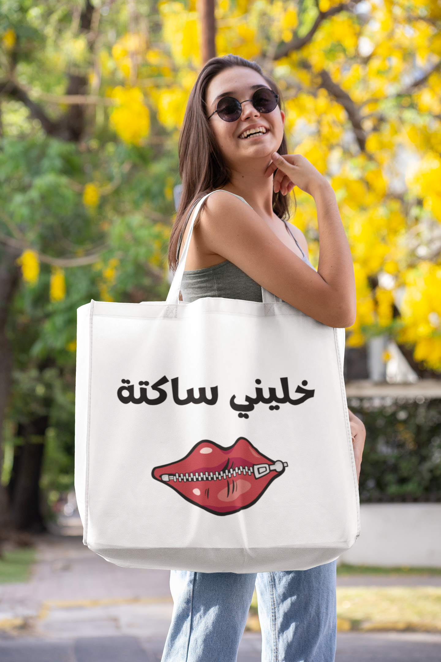 Jute bag with arabic text and red lips featuring a woman with sunglasses in front of a flowering tree