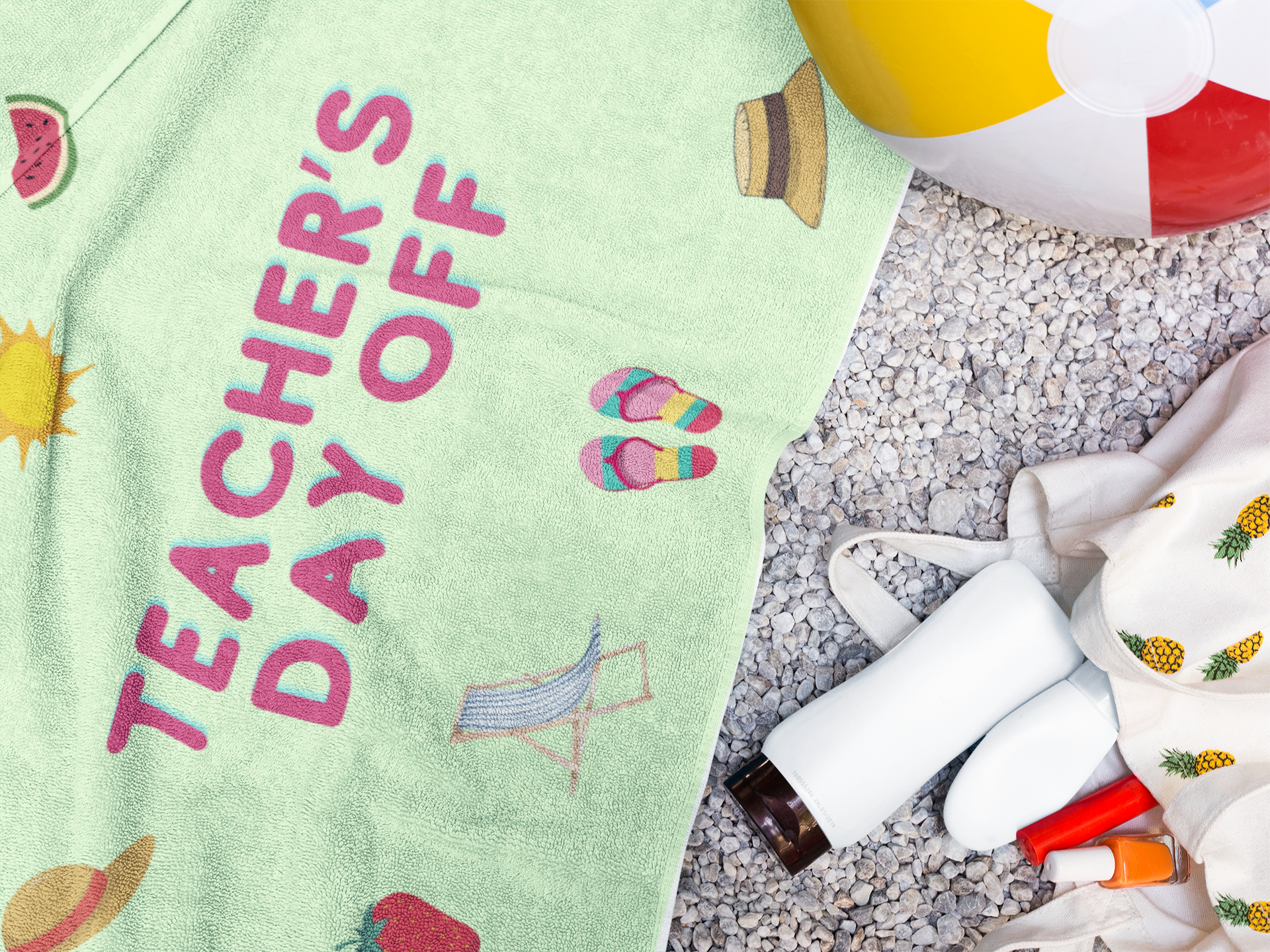 Green beach towel with “Teacher’s Day Off” print, surrounded by beach items