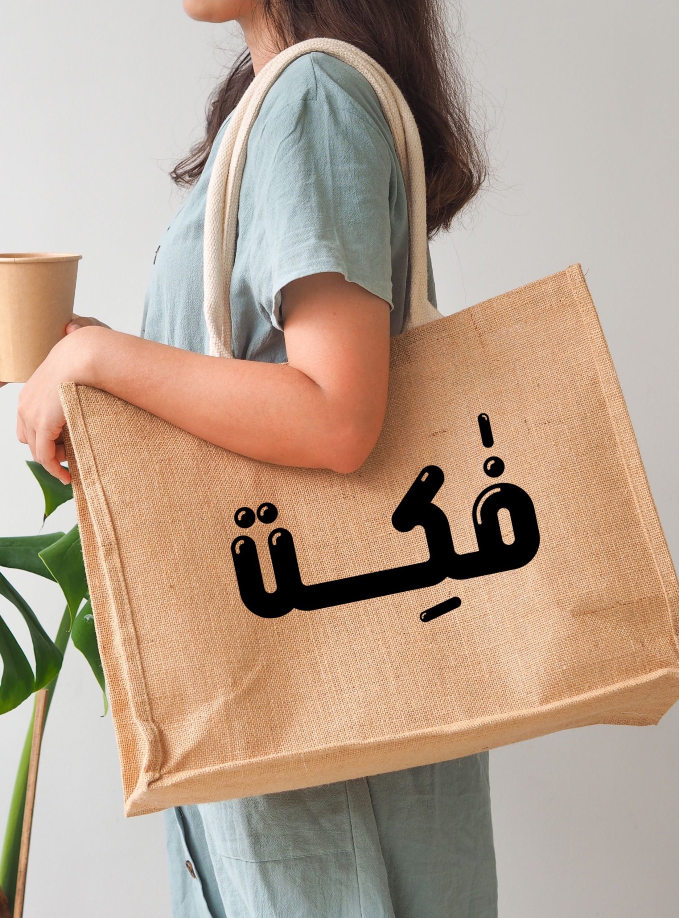 A lady pulling a brown tote bag with arabic text on it