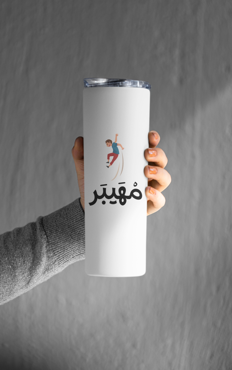 White tumbler with a design and text held by a hand against a gray background