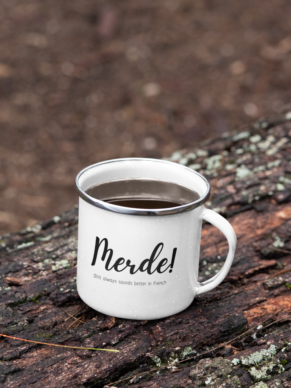 White mug with 'Merde!' text on a wooden surface