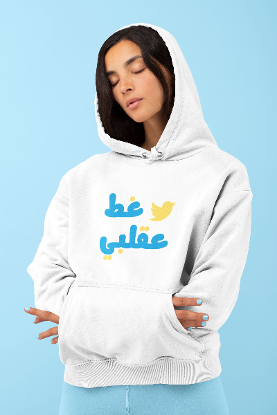 Person wearing a white hoodie with Arabic text and a bird icon on a blue background