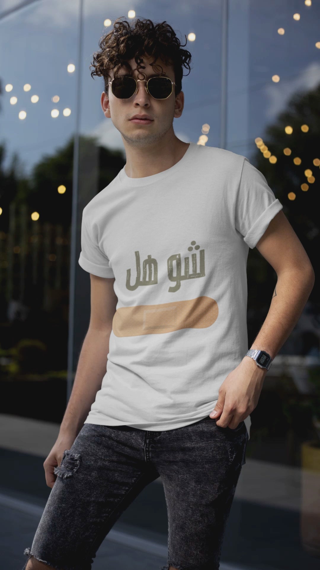 Man wearing white T-shirt with Arabic text and band-aid design, urban background